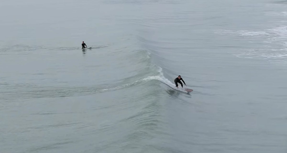 Sharing the peaks on a quiet grey session, a couple of locals trading waves, New Brighton surf spot, Canterbury, New Zealand.