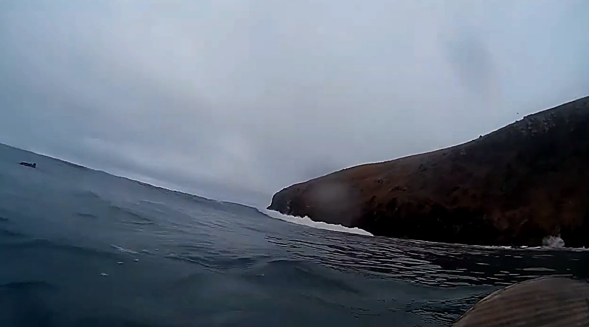 Watching the wave wrap around the headland from the water, the long right setting up, Whareakeake / Murdering Bay surf spot, 